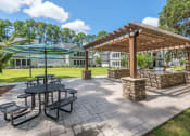 Thumbnail 15 of 20 - a picnic area with tables and umbrellas at the enclave at woodbridge apartments in sugar