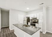 Thumbnail 9 of 35 - A kitchen with a black granite countertop and white cabinets.