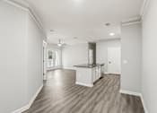 Thumbnail 10 of 35 - A spacious kitchen with white cabinets and a wooden floor.