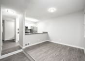 Thumbnail 10 of 17 - an empty living room with a kitchen in the background