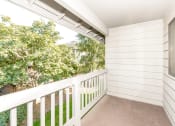 Thumbnail 9 of 17 - a balcony with a white railing and trees in the background