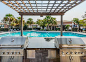 Thumbnail 19 of 20 - two gas bbq grills with a pool in the background