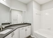 Thumbnail 12 of 35 - A white bathroom with a sink, mirror, and bathtub.