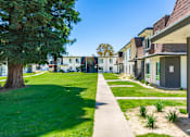 Thumbnail 2 of 36 - a row of houses on a grassy area with trees in the background