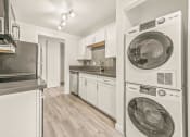 Thumbnail 11 of 42 - a kitchen with white cabinetry and a washer and dryer