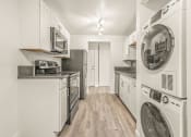 Thumbnail 9 of 42 - a kitchen with white cabinetry and a washer and dryer