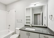 Thumbnail 16 of 35 - A white bathroom with a black counter top and a white toilet.