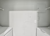 Thumbnail 19 of 35 - A white washing machine sits in a laundry room.