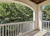 Thumbnail 32 of 35 - A balcony with a white railing and a view of a wooded area.