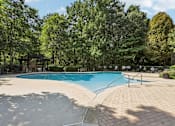 Thumbnail 30 of 35 - A large outdoor swimming pool surrounded by trees.