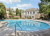 Thumbnail 4 of 35 - A swimming pool in front of a house with a brick wall.