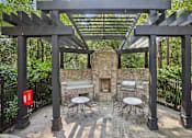 Thumbnail 34 of 35 - A patio with a fireplace and chairs under a pergola.