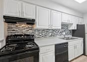 Thumbnail 66 of 98 - A kitchen with black and white appliances and cabinets.