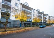 Thumbnail 36 of 42 - an apartment building with a blue car parked in front of it