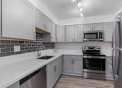 Thumbnail 2 of 28 - A kitchen with a stainless steel refrigerator, oven, and microwave.