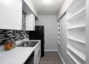 Thumbnail 27 of 43 - a renovated kitchen with white cabinets and a black refrigerator