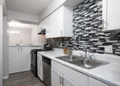 Thumbnail 28 of 43 - a renovated kitchen with white cabinets and a stainless steel sink