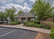 Thumbnail 11 of 34 - a small brick building with a driveway and trees and bushes