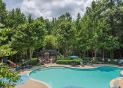 Thumbnail 9 of 34 - a swimming pool with chairs around it and trees in the background