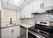 Thumbnail 31 of 33 - a kitchen with white cabinets and black appliances and a sink