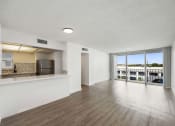 Thumbnail 18 of 33 - the living room and kitchen of an apartment with wood flooring and a large window