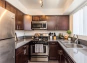 Thumbnail 2 of 9 - a kitchen with dark wood cabinets and stainless steel appliances