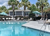 Thumbnail 2 of 20 - a resort style pool with chaise lounge chairs and umbrellas