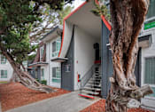 Thumbnail 26 of 36 - a building with a gray and red exterior and two large trees in front of it