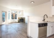 Thumbnail 22 of 42 - a kitchen with white cabinets and a dishwasher and a living room with a fireplace