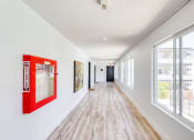 Thumbnail 12 of 24 - a long hallway with large windows and a red picture frame on the wall