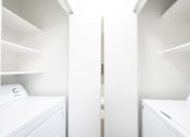 Thumbnail 18 of 25 - a washer and dryer in a laundry room with white walls and white shelves
