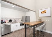 Thumbnail 9 of 25 - a kitchen with white cabinets and a wooden table with three stools