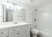 Thumbnail 8 of 46 - A white bathroom with a sink, mirror, toilet and bathtub.