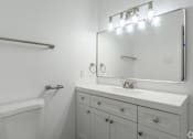 Thumbnail 7 of 46 - A white bathroom with a white toilet, sink, and vanity.