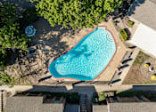 Thumbnail 1 of 46 - An aerial view of a swimming pool surrounded by trees and buildings.