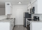 Thumbnail 4 of 46 - A kitchen with white cabinets and black appliances.