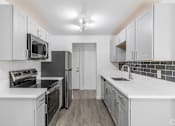 Thumbnail 44 of 48 - A kitchen with white cabinets and black appliances.
