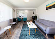 Thumbnail 21 of 29 - a living room with a couch coffee table and chairs and a dining room table in the background