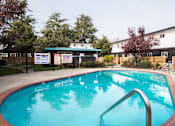 Thumbnail 2 of 29 - a swimming pool with a fence and buildings in the background