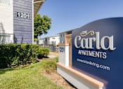 Thumbnail 4 of 17 - a sign that says the carla apartments with a building in the background