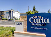 Thumbnail 2 of 17 - a sign that says the carla apartments with houses in the background