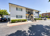 Thumbnail 15 of 17 - a white apartment building with a black car parked in front of it