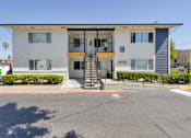 Thumbnail 16 of 17 - a white apartment building with a staircase and a parking lot in front of it