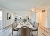 Thumbnail 7 of 15 - a dining area with a long table and chairs and a kitchen in the background