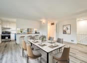 Thumbnail 8 of 15 - a dining area with a long table and chairs and a kitchen in the background