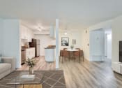 Thumbnail 4 of 15 - a living room with a couch a table and a chair and a kitchen in the background