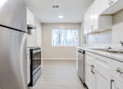 Thumbnail 4 of 25 - A kitchen with white cabinets and a black fridge.