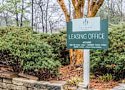 Thumbnail 14 of 25 - A sign for The Pynes Leasing Office is displayed in front of a hedge.