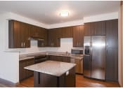 Thumbnail 6 of 23 - a kitchen with dark wood cabinets and granite countertops