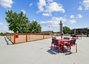 Thumbnail 22 of 22 - A table and chairs set up on a sandy surface with trees in the background.